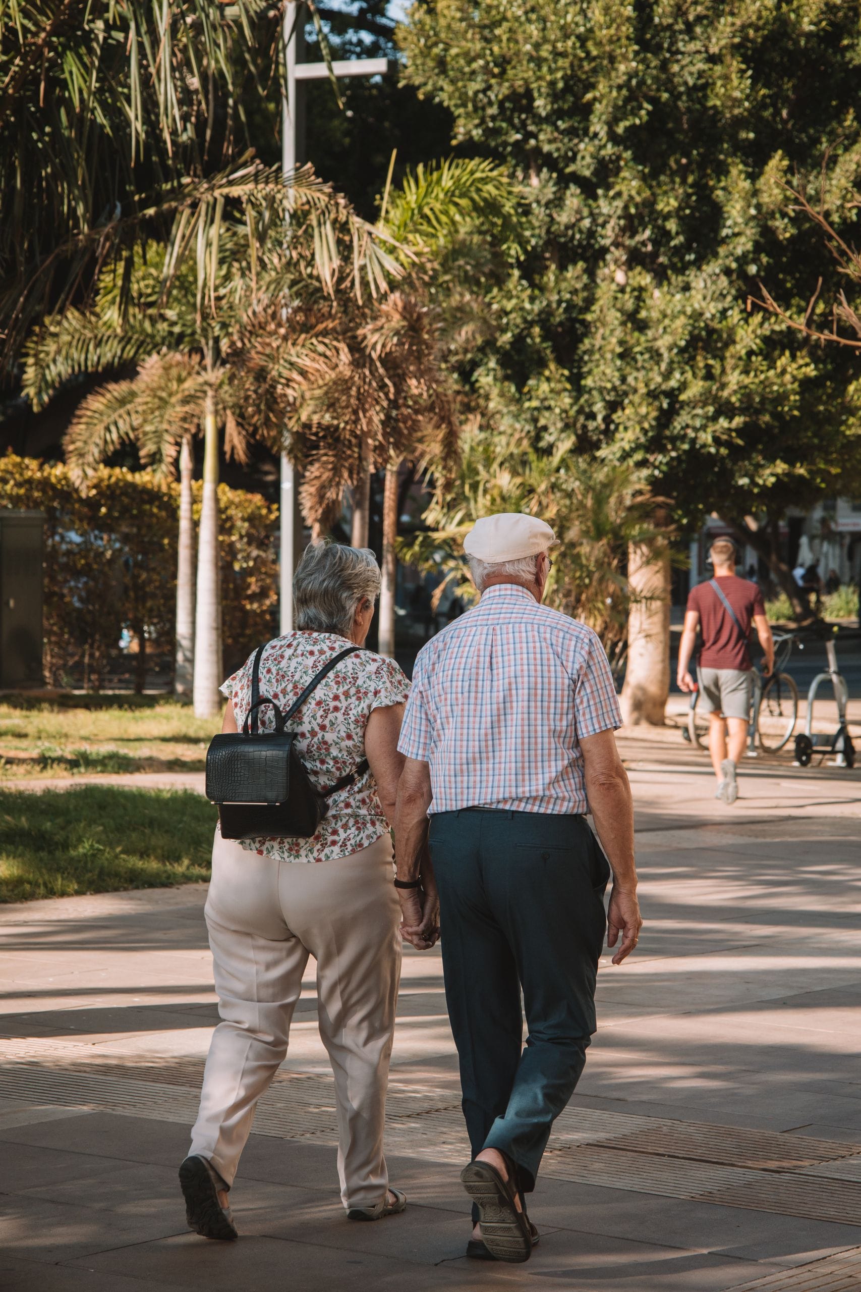 Elderly couple strolling hand in hand on a sunny day in Málaga, Spain.